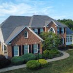 Residential home with asphalt shingle roofing, brick exterior, and landscaped yard, representing local expertise in Pittsburgh roofing solutions.