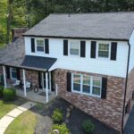 Residential building with a modern roof design, featuring a combination of brick and siding, surrounded by landscaped lawn, illustrating quality roofing solutions for homes.