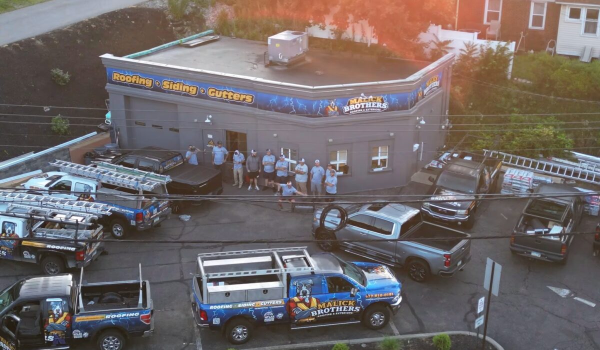 Malick Brothers Exteriors building with team members and branded trucks showcasing roofing, siding, and gutter services in Pittsburgh.