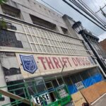 Thrift store building with large sign, scaffolding, and construction materials, representing local commercial retail space in need of roofing solutions.