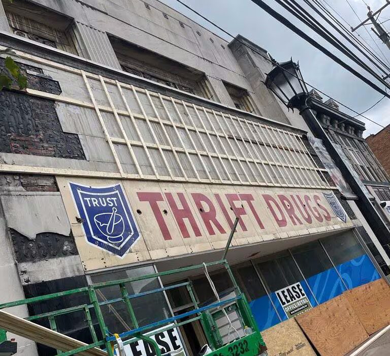 Thrift Drugs storefront with "THRIFT DRUGS" sign and "LEASE" notice, surrounded by construction equipment and a lamppost, highlighting commercial property trends in Pittsburgh.
