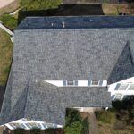 Aerial view of a residential roof with gray shingles, showcasing roofing structure relevant to Pittsburgh commercial roofing and warranty discussions.