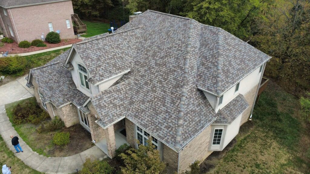 Aerial view of a residential home in Pittsburgh with a newly installed asphalt shingle roof, showcasing proper roofing materials and design to withstand local climate challenges.