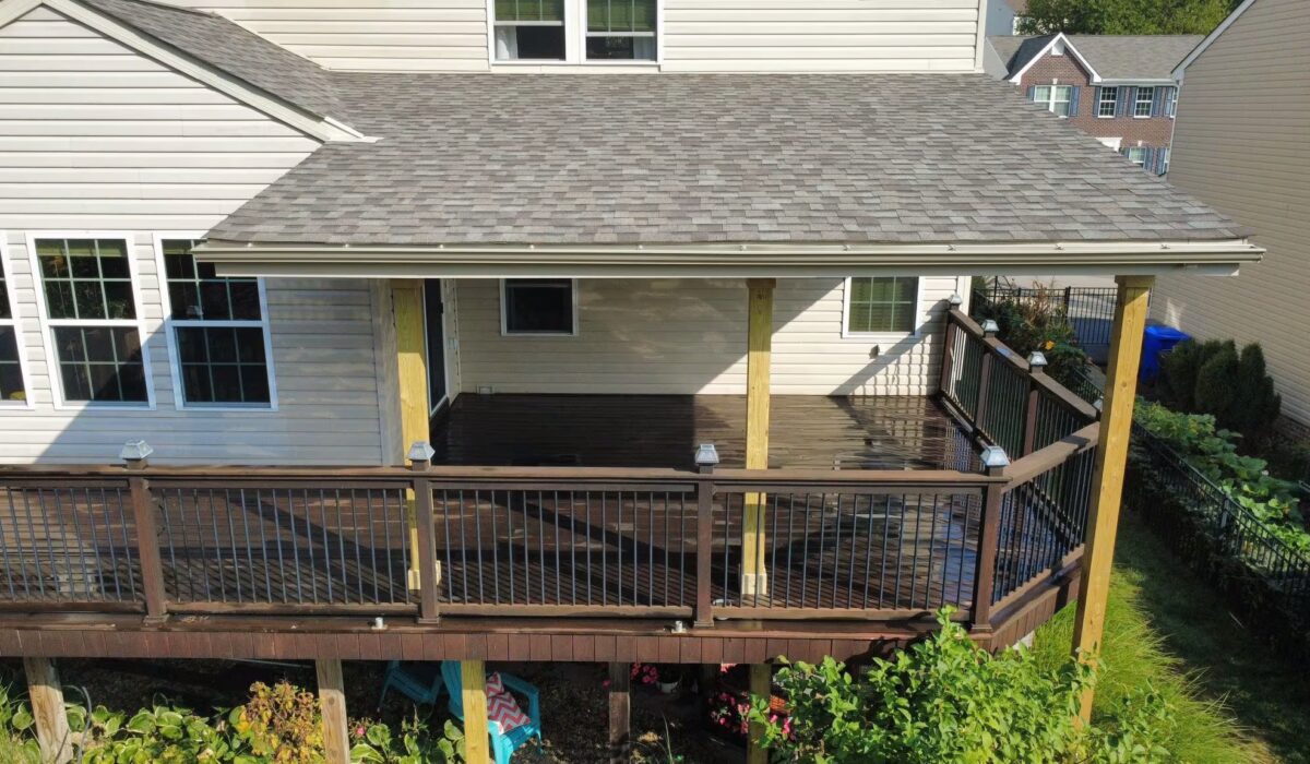 Newly constructed porch with a shingled roof, wooden railing, and a view of a residential backyard, illustrating quality craftsmanship in exterior solutions by Malick Brothers Exteriors.