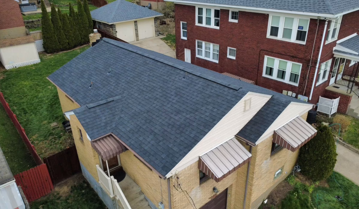 Aerial view of a residential building in Pittsburgh with a newly installed asphalt shingle roof, showcasing effective drainage design to manage rainwater in a climate prone to heavy precipitation.