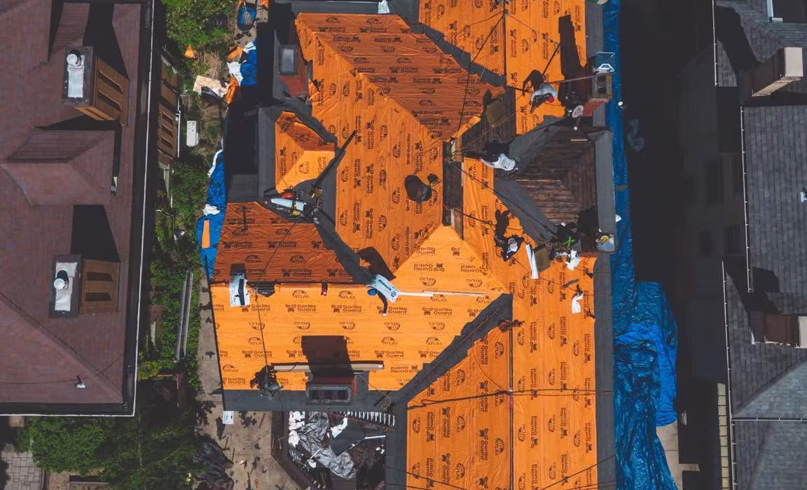 Commercial roof installation with orange roofing membrane and workers, Pittsburgh Pennsylvania.