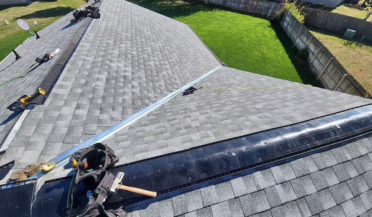 Roofers installing ridge venting and new asphalt shingles on a residential roof