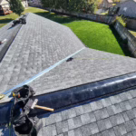 Roofers installing ridge venting and new asphalt shingles on a residential roof