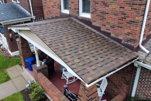 Aerial view of a brick home with asphalt shingle porch roofing and wall flashing