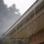 Heavy rain overflowing from a residential roof gutter during a storm