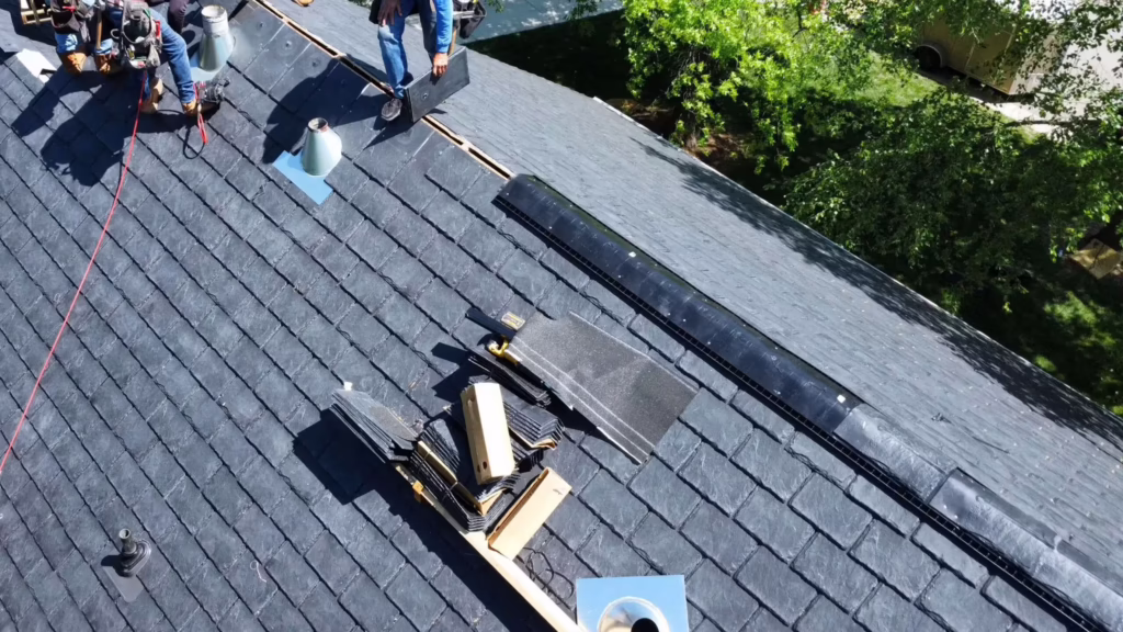 Roofing crew installing ridge ventilation and ridge cap shingles on a residential roof