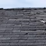 Severely damaged asphalt roof with curled, cracked, and deteriorated shingles