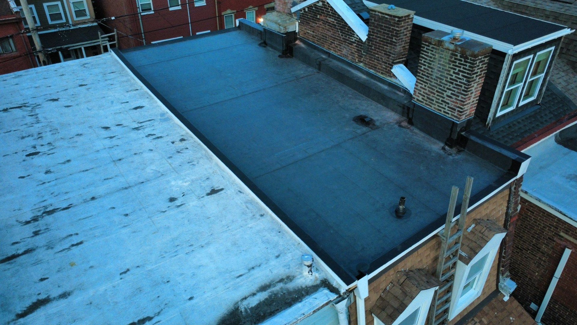 Flat roof between brick rowhouses installed by Malick Brothers Exteriors in Pittsburgh