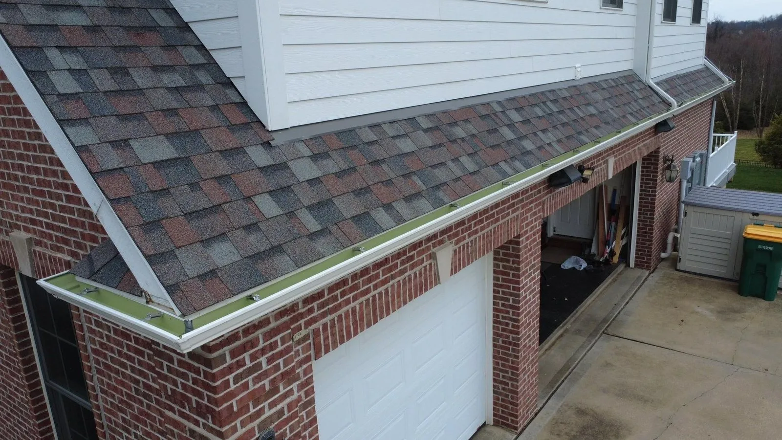New white seamless gutter along the garage roof edge of a brick home in McCandless, installed by Malick Brothers Exteriors