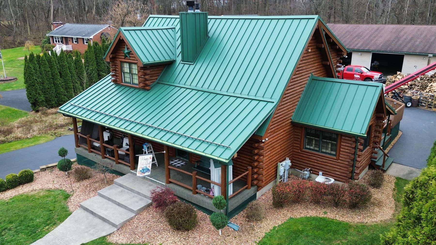 Green standing seam metal roof installed by Malick Brothers Exteriors on a log home