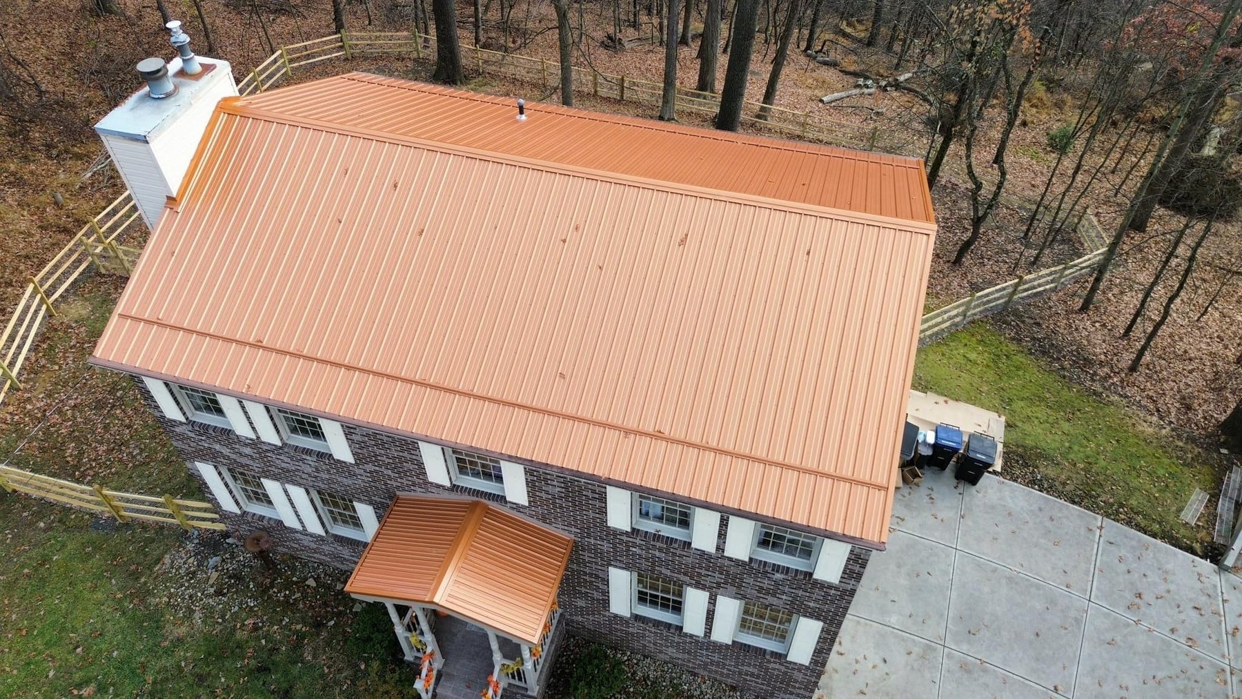 Copper colored metal roof installed by Malick Brothers Exteriors on a brick colonial