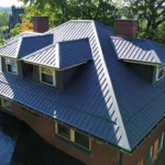 Charcoal standing seam metal roof installed by Malick Brothers Exteriors on a brick home