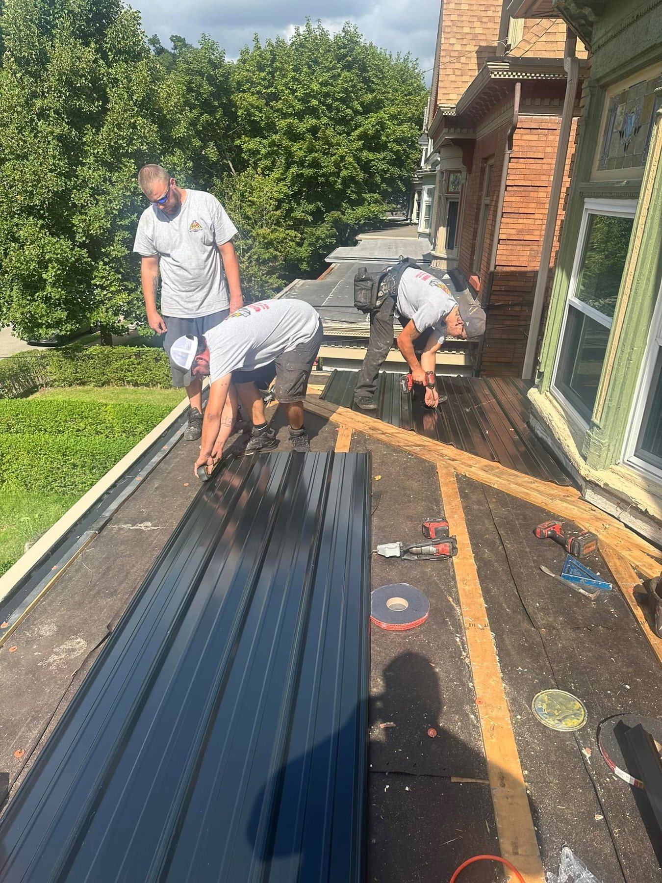 Malick Brothers crew installing dark metal roof panels on a porch roof