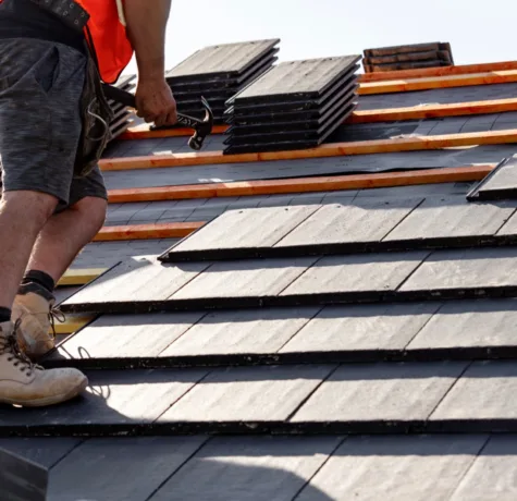 Roofer setting new slates on a roof