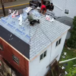 Roofing crew installing gray architectural shingles over synthetic underlayment during a roof replacement in Pittsburgh